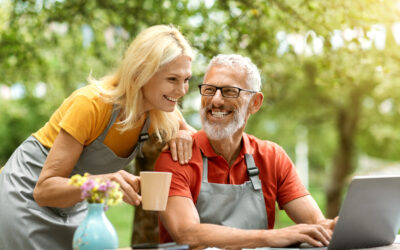 Modern Retirement Lifestyle. Happy senior couple using laptop outdoors at their terrace