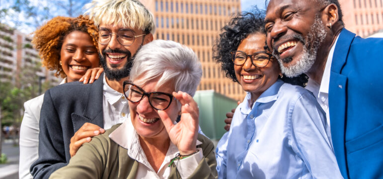 Mature businesswoman taking a selfie with colleagues outdoors