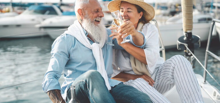 Senior couple toasting champagne on sailboat vacation - Happy el